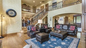 A spacious living room with leather sofas, a large rug, and a staircase leading to an upper level.