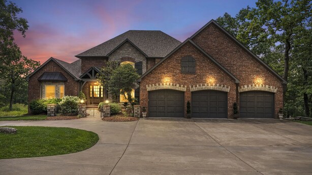 A large brick house with a spacious driveway and multiple garage doors.