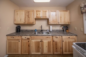 Kitchen features a sink, coffee maker, and toaster, with ample storage in cabinets above and below the countertop.