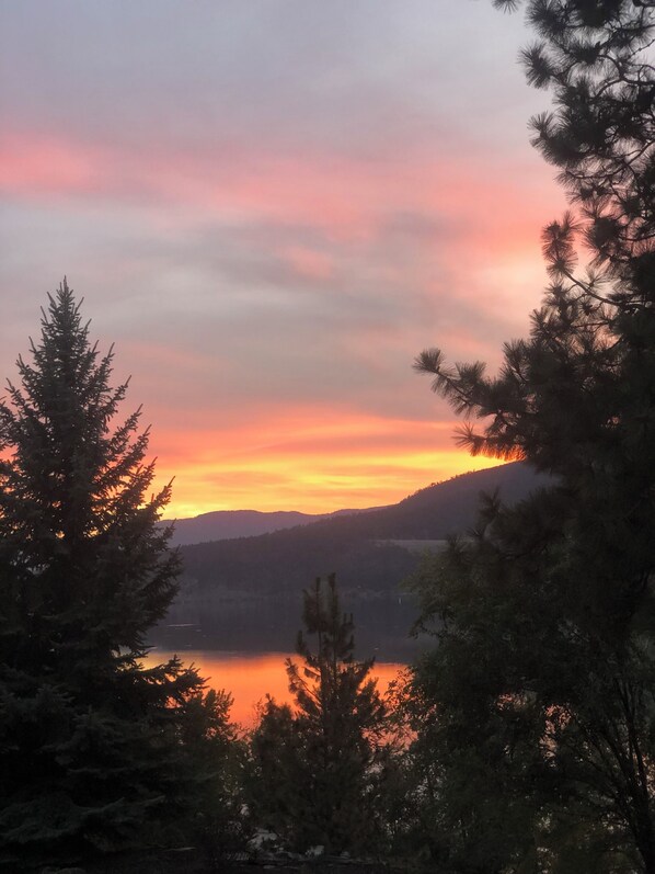 A sunset over a lake with trees in the foreground.