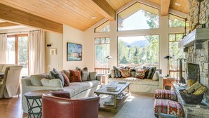 A spacious living room with high ceilings and large windows, a fireplace, and comfortable seating. - Elkhorn Summer Amenities and Mtn Views (Sun Valley)