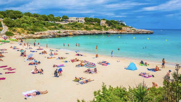 A beach with people sunbathing, swimming, and walking along the shore. - Ses Sivines – Traditional Mallorcan Villa with Private Pool, Free WiFi and Air C (Porto Colom)