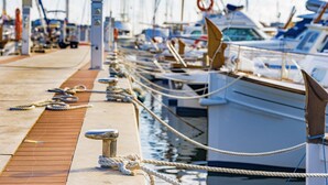 A marina with boats docked in a row, a wooden walkway, and ropes tied to bollards. - Ses Sivines – Traditional Mallorcan Villa with Private Pool, Free WiFi and Air C (Porto Colom)