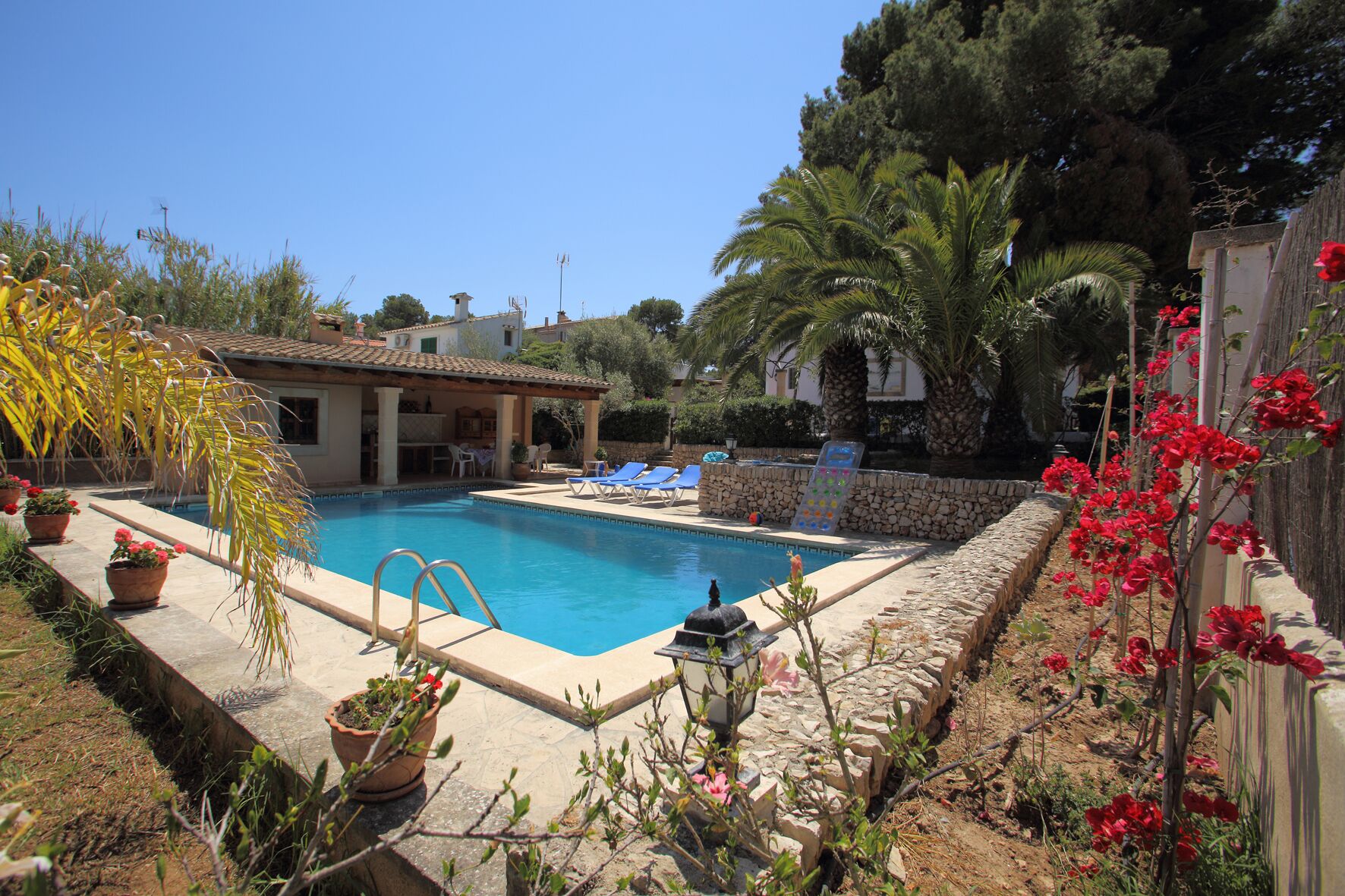 A swimming pool with a stone border, surrounded by potted plants and a stone wall.