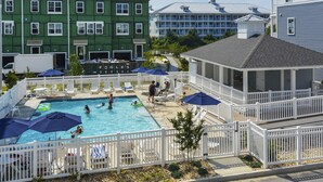 A swimming pool area with multiple pools, surrounded by a white fence, and various umbrellas. - Brand New! 4-Br Bayside Townhome, Water and Pool View, Beach 1 block,  Free WiFi (Ocean City)