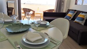 A dining area with a table set for two, including plates, cutlery, and a wine glass. - MiraPraia 7- Refurbished, Air Conditioning, Wifi, TV, Bedroom and Living Room, Sea View (Quarteira)