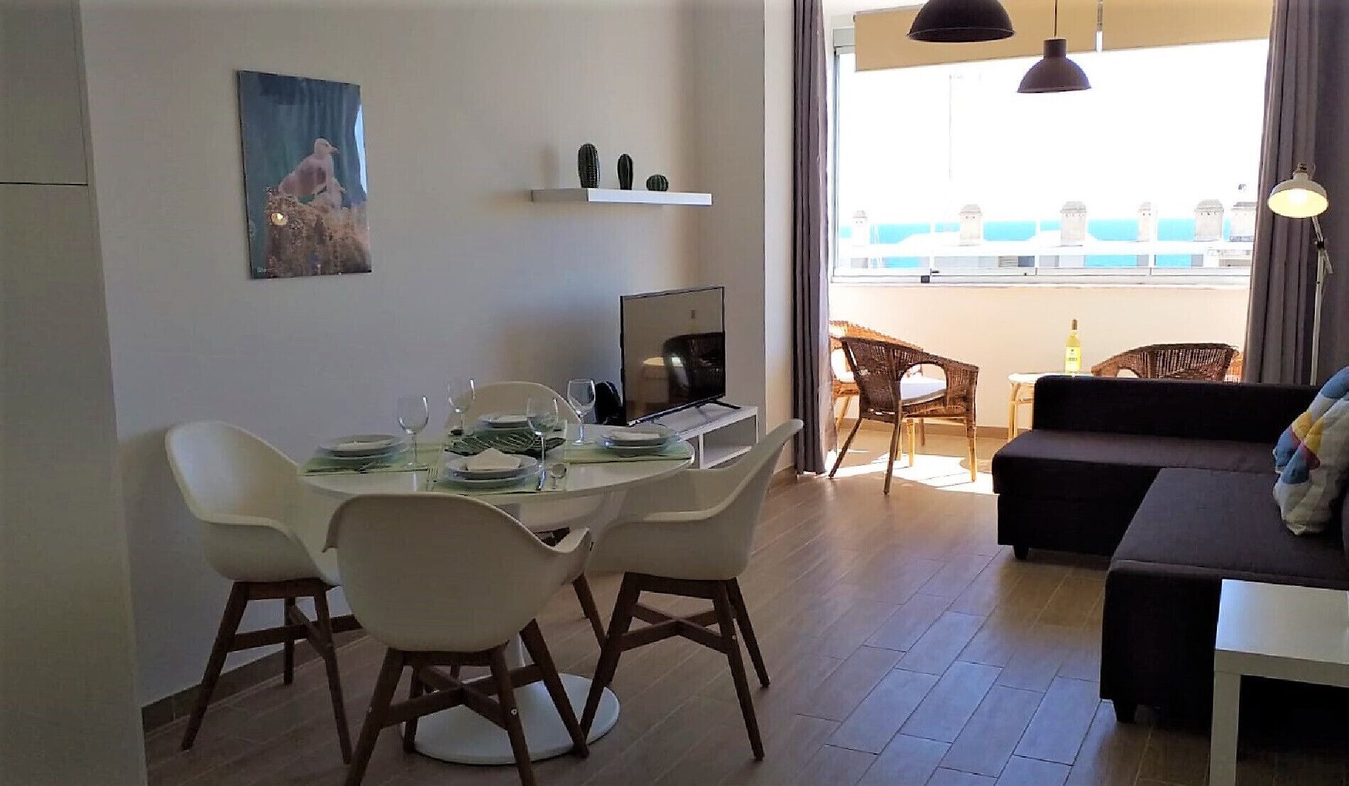 Ein modernes Wohnzimmer mit Essbereich, einem Flachbildfernseher und einem Balkon mit Aussicht.
