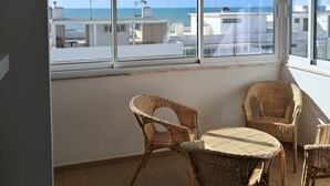 A balcony with wicker furniture, large windows, and a view of the sea. - MiraPraia 7- Refurbished, Air Conditioning, Wifi, TV, Bedroom and Living Room, Sea View (Quarteira)