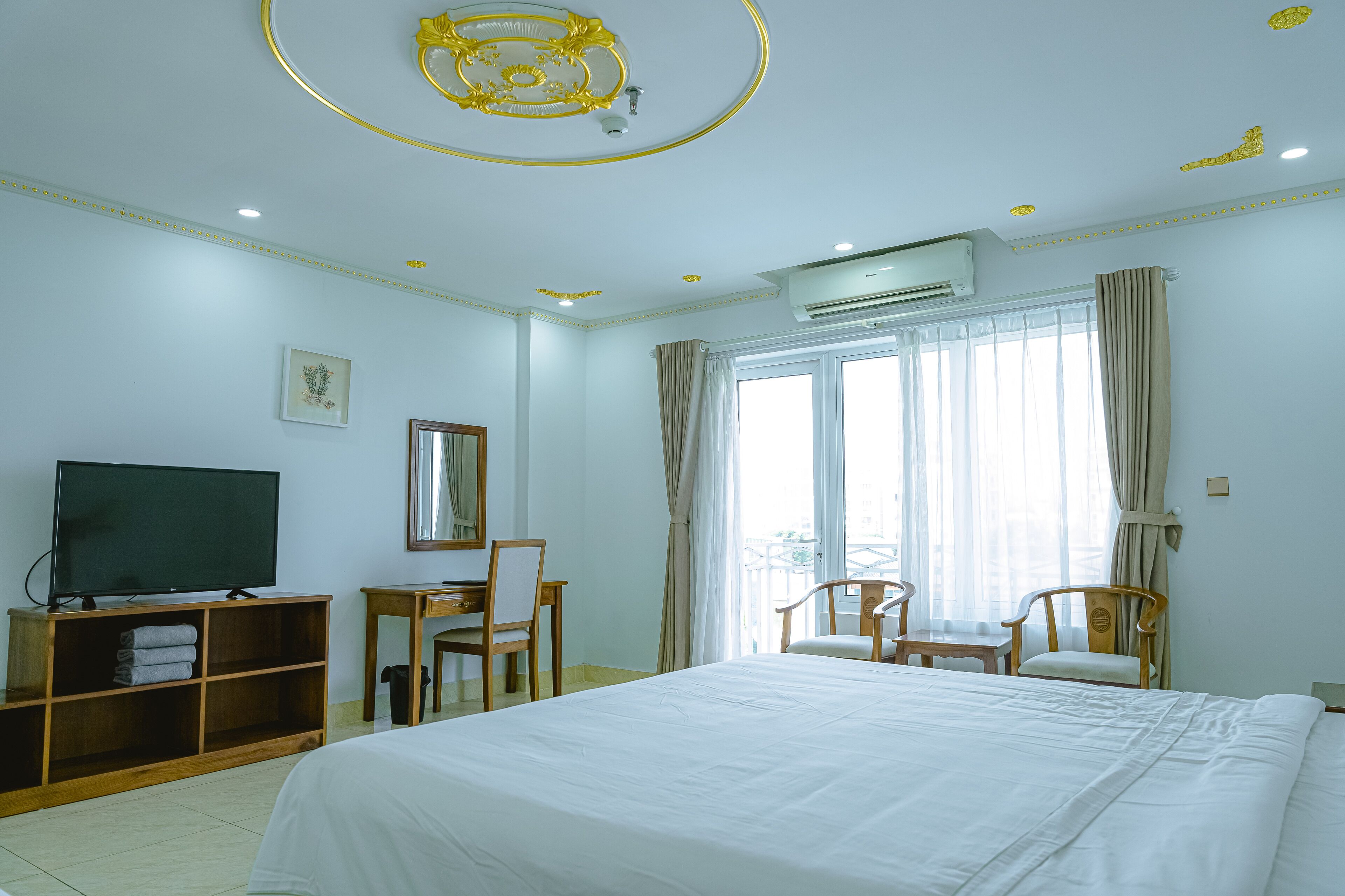 Ein Hotelzimmer mit einem großen Bett, einem Fernseher, einem Schreibtisch und zwei Sesseln.