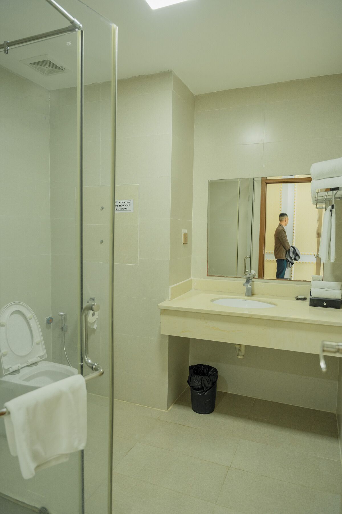 A bathroom with a glass-enclosed shower, a toilet, a sink with a mirror, and a towel rack.