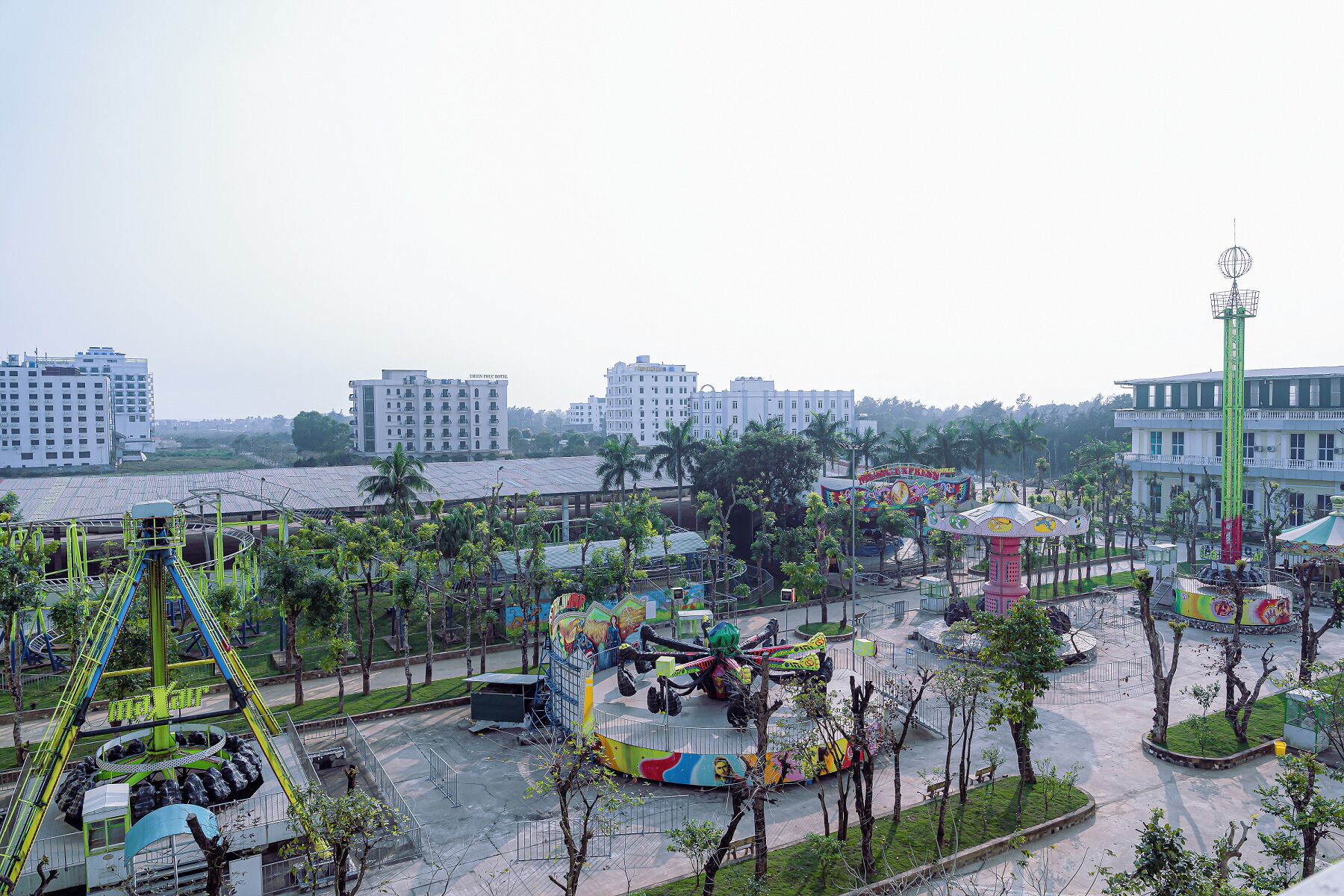 Un grand parc d’attractions proposant de nombreux manèges et attractions, entouré de bâtiments et de verdure.