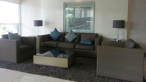 A modern living room with a sofa set, a coffee table, and two floor lamps. - Jericho's Place at Sea Residences (Pasay)