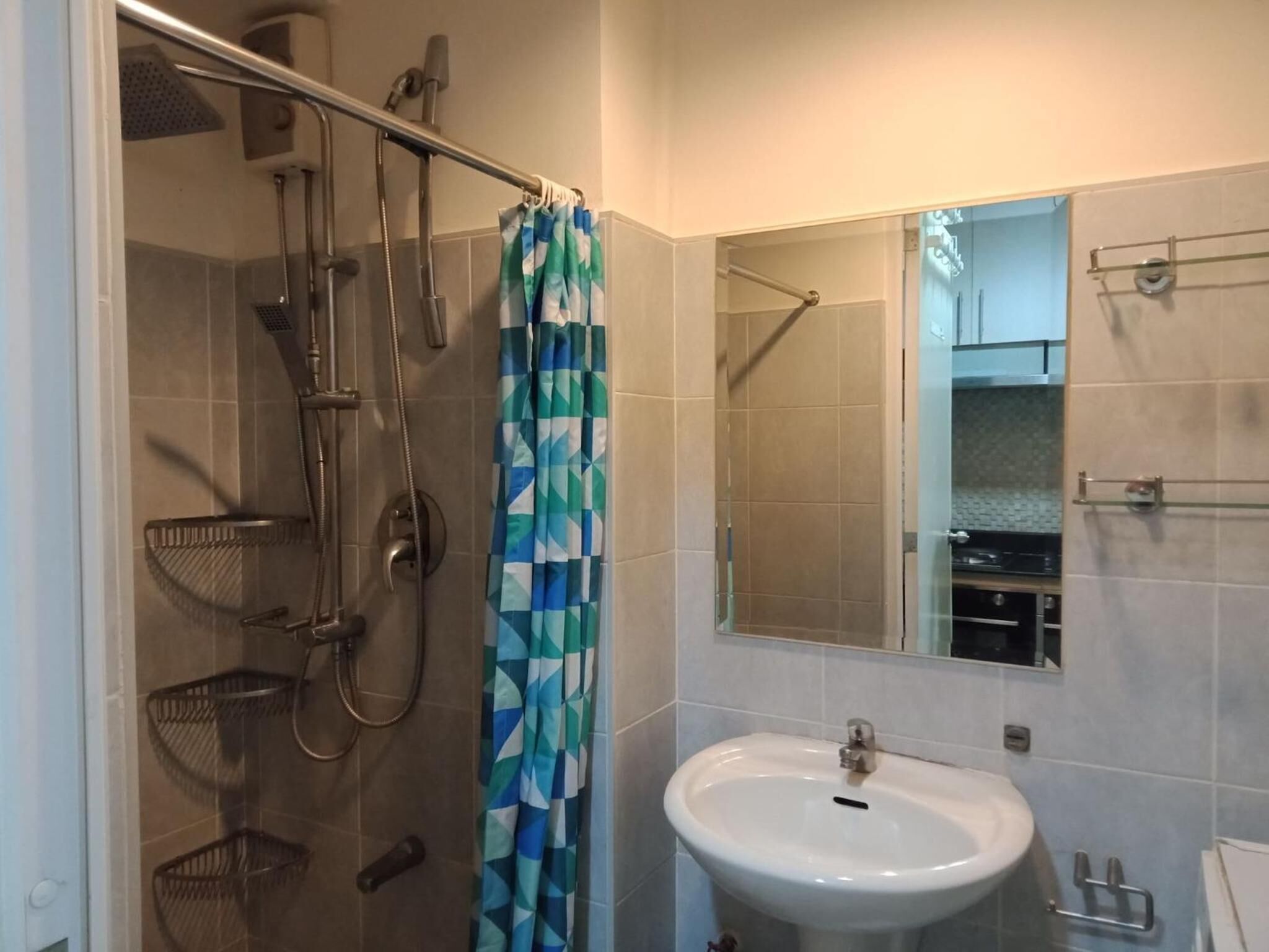 A bathroom with a shower, a sink, and a mirror.