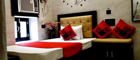 Une chambre d’hôtel comprenant un lit, un climatiseur fixé au mur, un motif décoratif sur le mur et un petit meuble de rangement.