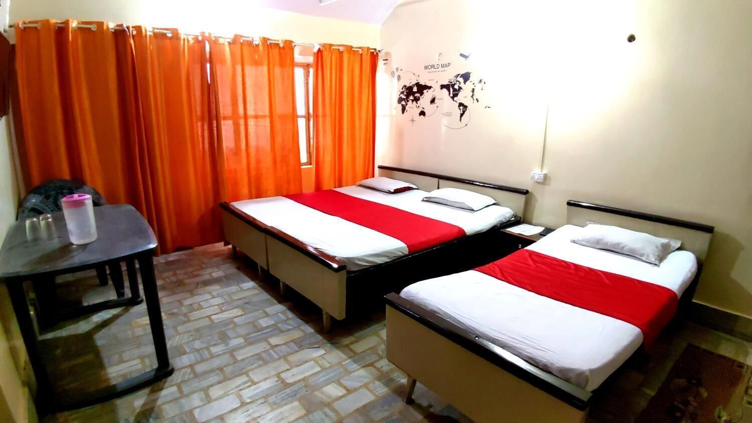 Habitación de hotel con dos camas, una mesita pequeña y un mapa del mundo en la pared.