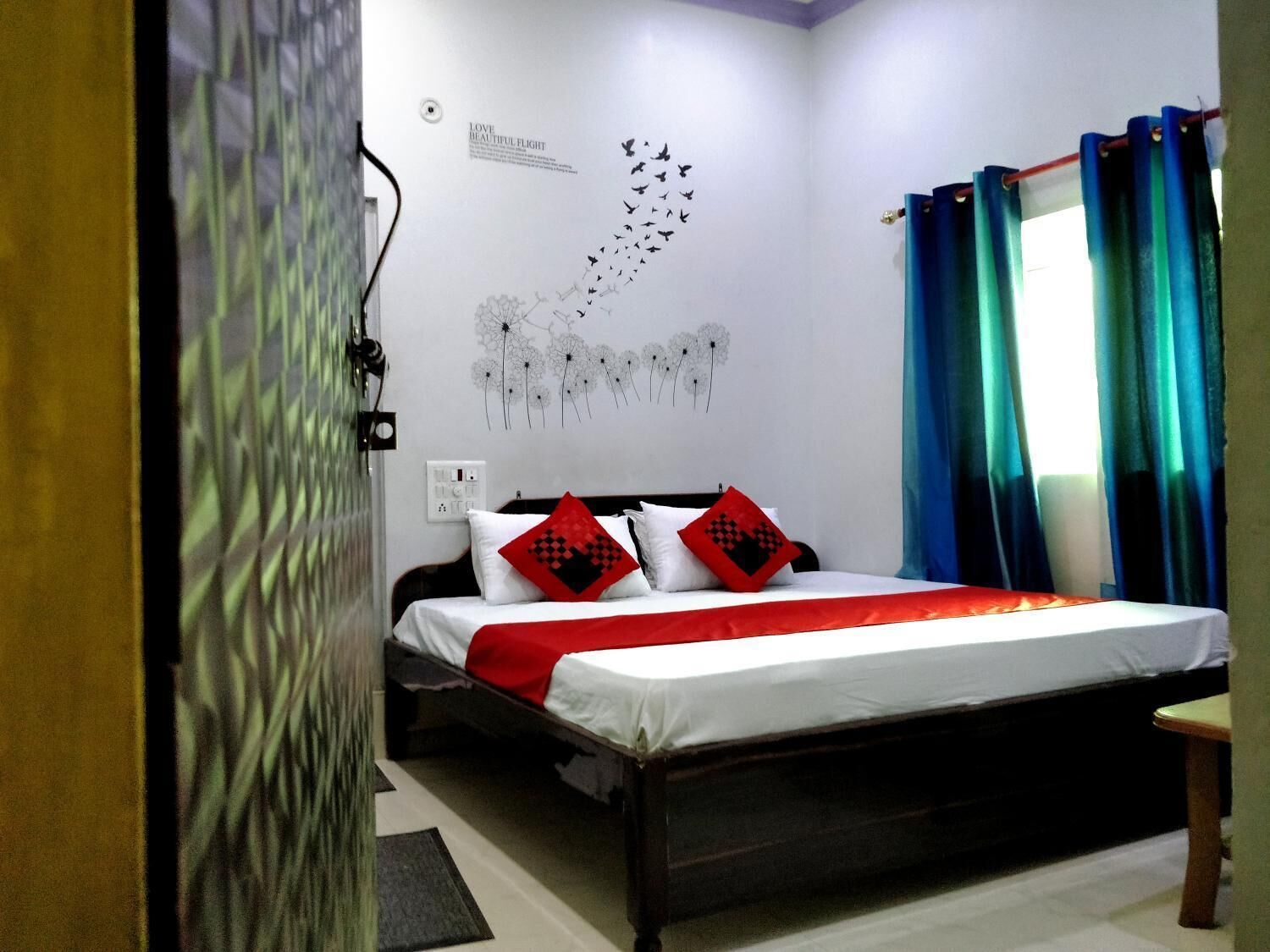 A bedroom with a bed, a wall with a bird migration pattern, and a window with curtains.