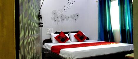 A bedroom with a bed, a wall with a bird migration pattern, and a window with curtains.
