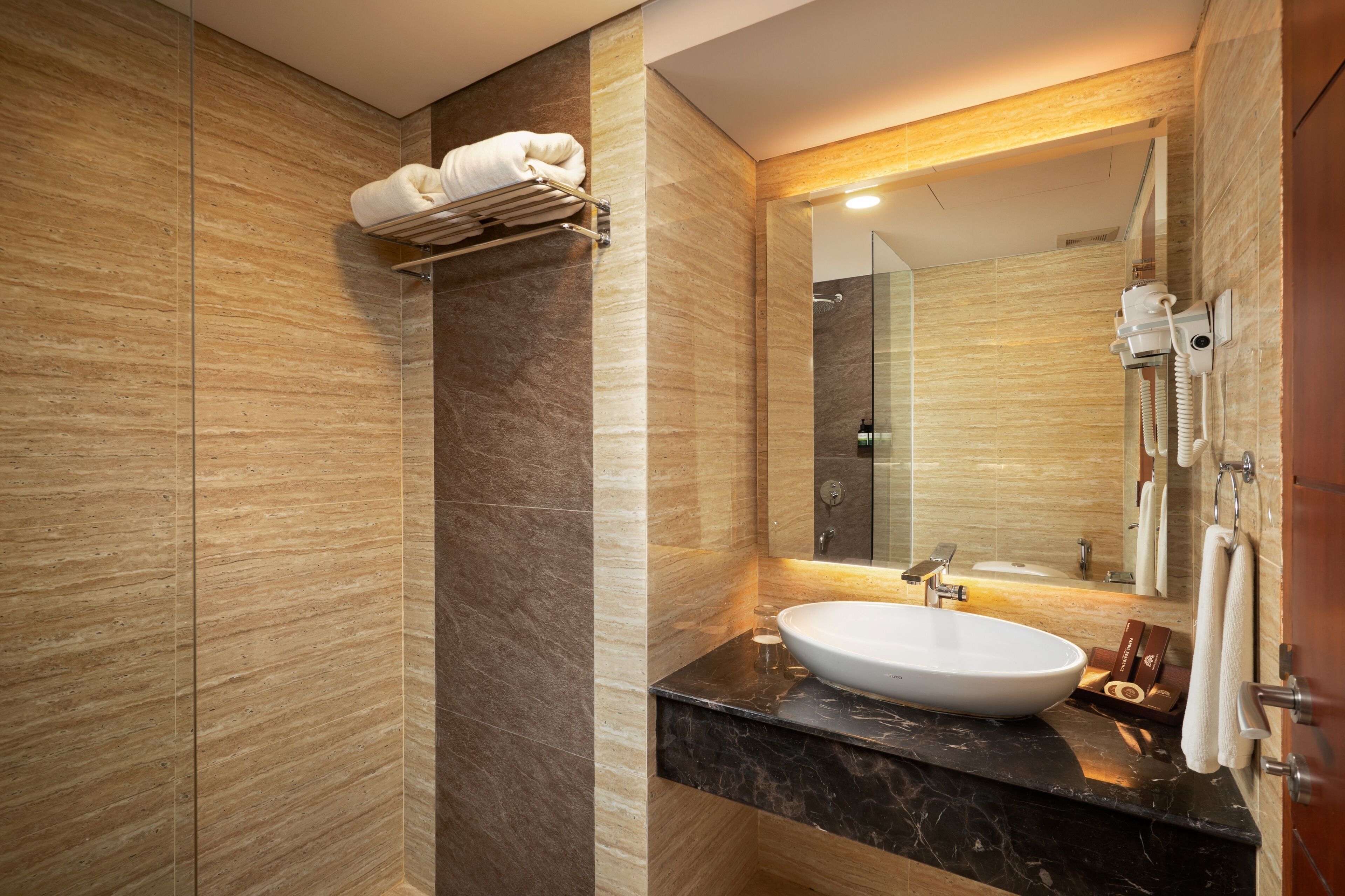 A modern bathroom with a marble sink, a towel rack, and a large mirror.