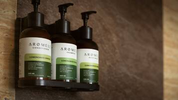 Trois bouteilles de gel douche et d’après-shampoing Arôme sont posées sur une étagère.