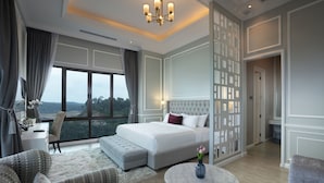 Un dormitorio amplio con una cama grande, una zona de estar con sofá y sillón, una mesita y vistas al exterior.