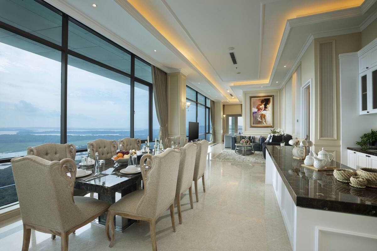 Un comedor amplio con una mesa grande, sillas elegantes y vista al océano.
