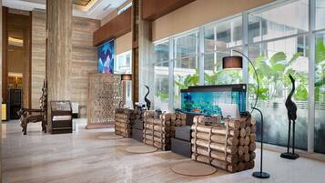 A lobby with a large aquarium, wooden reception desk, and a modern chandelier.