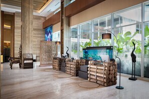 A lobby with a large aquarium, wooden reception desk, and a modern chandelier.