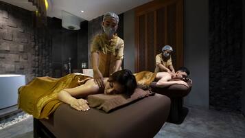 A massage therapy room with a stone wall, a wooden panel, and a modern light fixture.