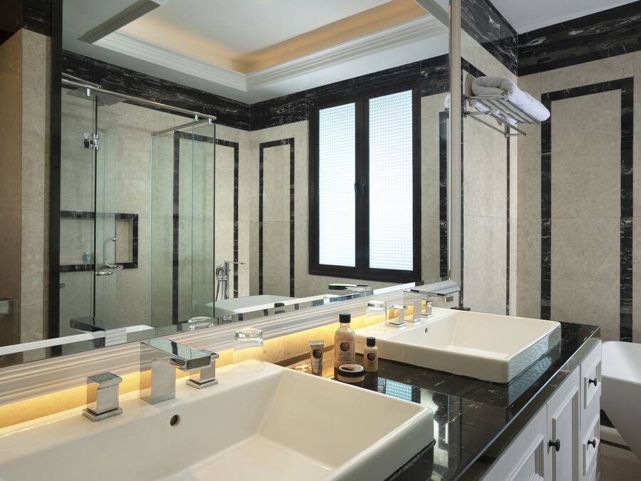 Un baño moderno con dos lavamanos grandes, una cabina de ducha de vidrio y un espejo amplio.