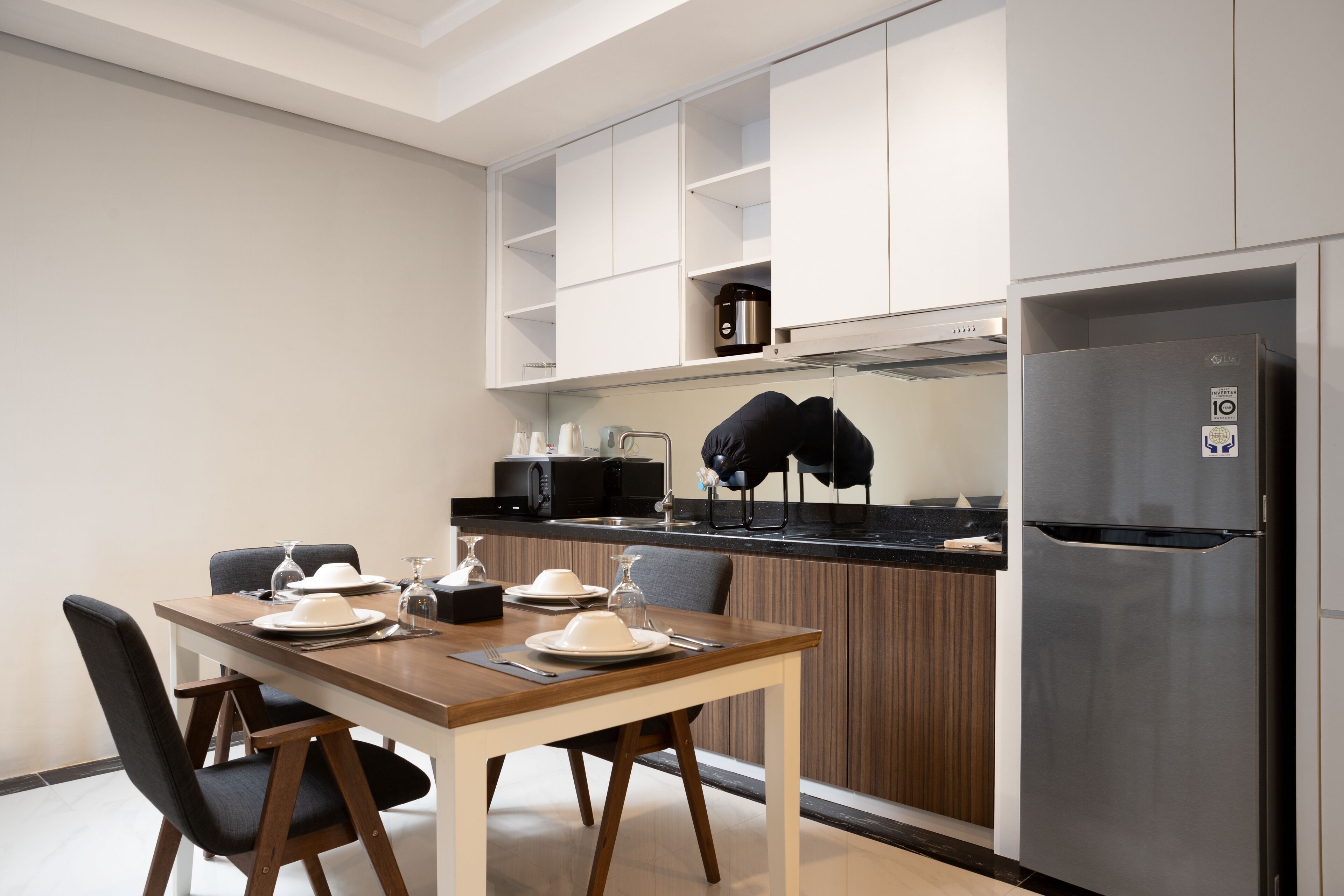 Une cuisine moderne avec une table à manger pour quatre personnes, un réfrigérateur en acier inoxydable et un four à micro-ondes.