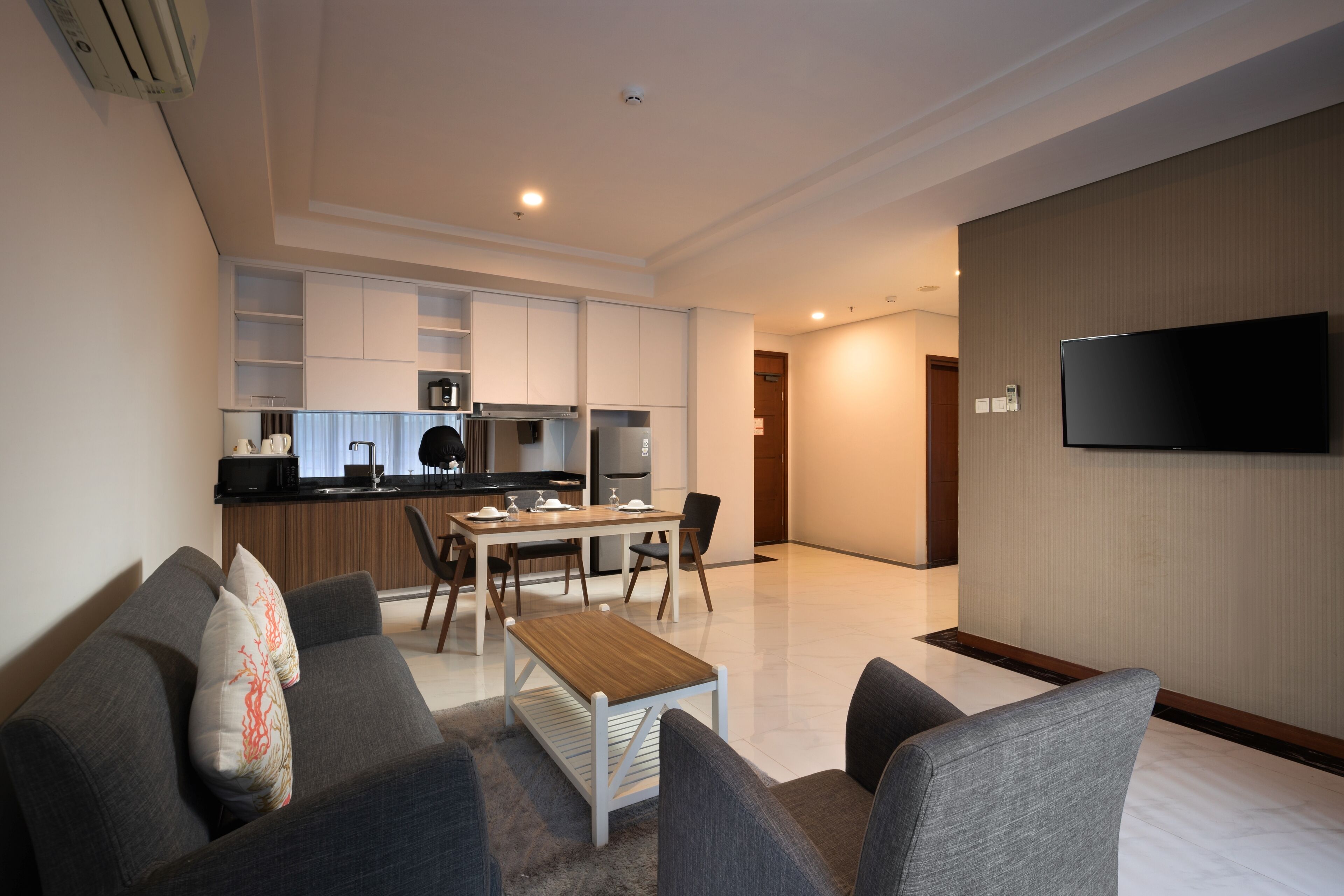 A modern living room with a grey sofa, a wooden coffee table, and a flat-screen TV mounted on the wall.