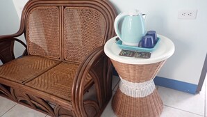 A wicker chair with a white and blue footrest, a blue kettle, and a blue mug on the footrest. - Da Peng Bay homestay (Linbian)