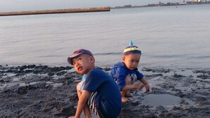 Two children playing in the mud by a calm body of water with a wooden dock in the background. - Da Peng Bay homestay (Linbian)