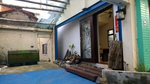 A small courtyard with a blue floor, a glass fish tank, a wooden bench, and a decorative door. - Da Peng Bay homestay (Linbian)