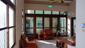 A spacious lobby with large windows, a ceiling fan, and a wooden reception desk. - Da Peng Bay homestay (Linbian)