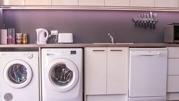 Une cuisine moderne équipée d’appareils électroménagers intégrés, notamment un lave-linge, un lave-vaisselle et un four à micro-ondes.
