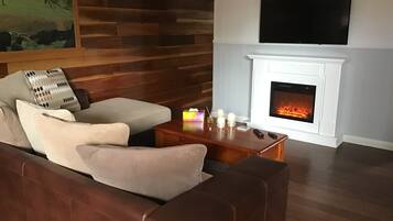 A living room with a fireplace, a sofa, a coffee table, and a TV mounted on the wall.
