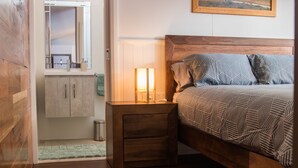 Un dormitorio con cama de madera, una mesita de noche con lámpara, un armario de madera y una alfombra verde.
