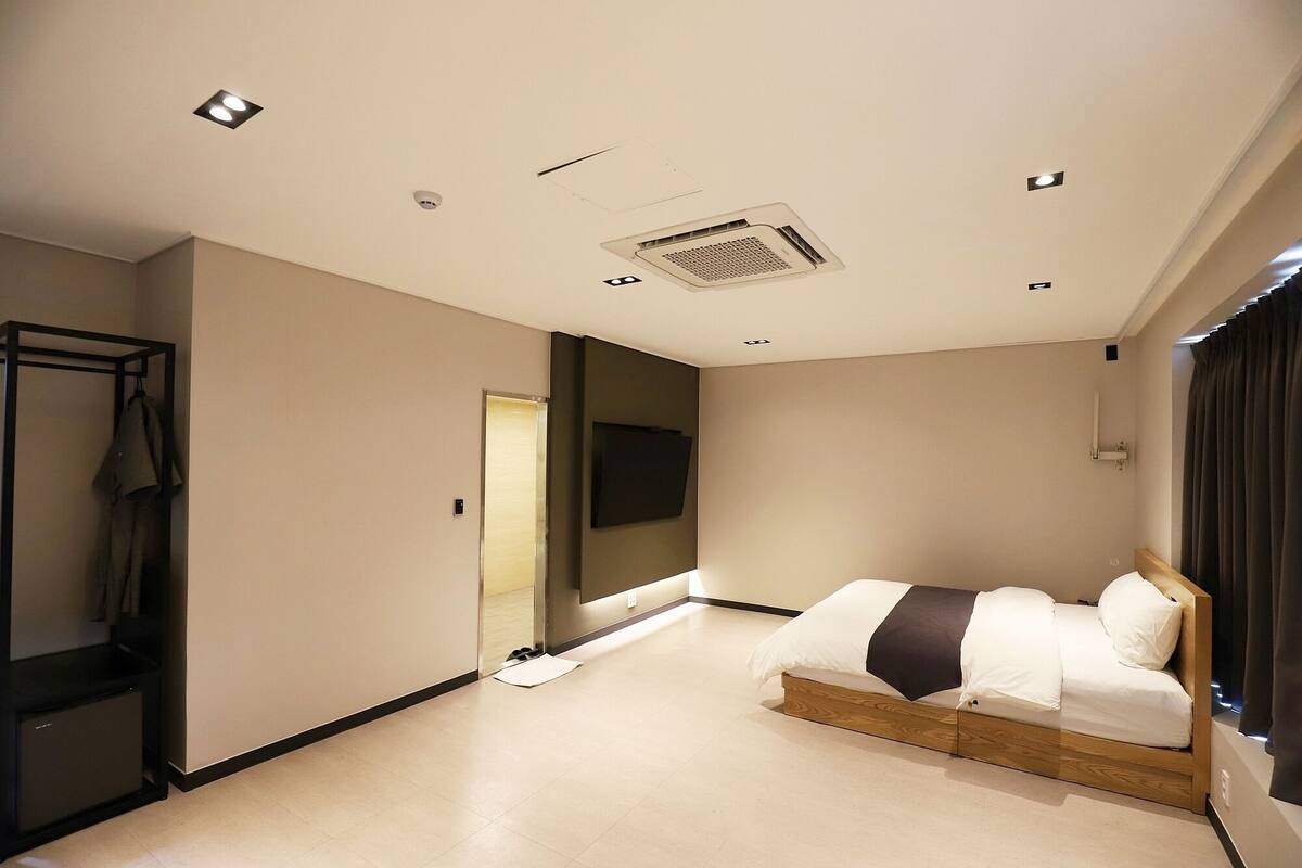 Une chambre d’hôtel moderne équipée d’un lit, d’une armoire et d’un miroir.
