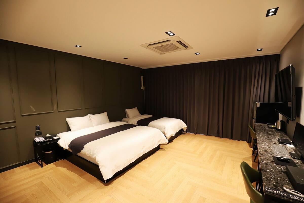 Une chambre d’hôtel avec deux lits, un bureau avec un ordinateur, une télévision à écran plat et un minibar.