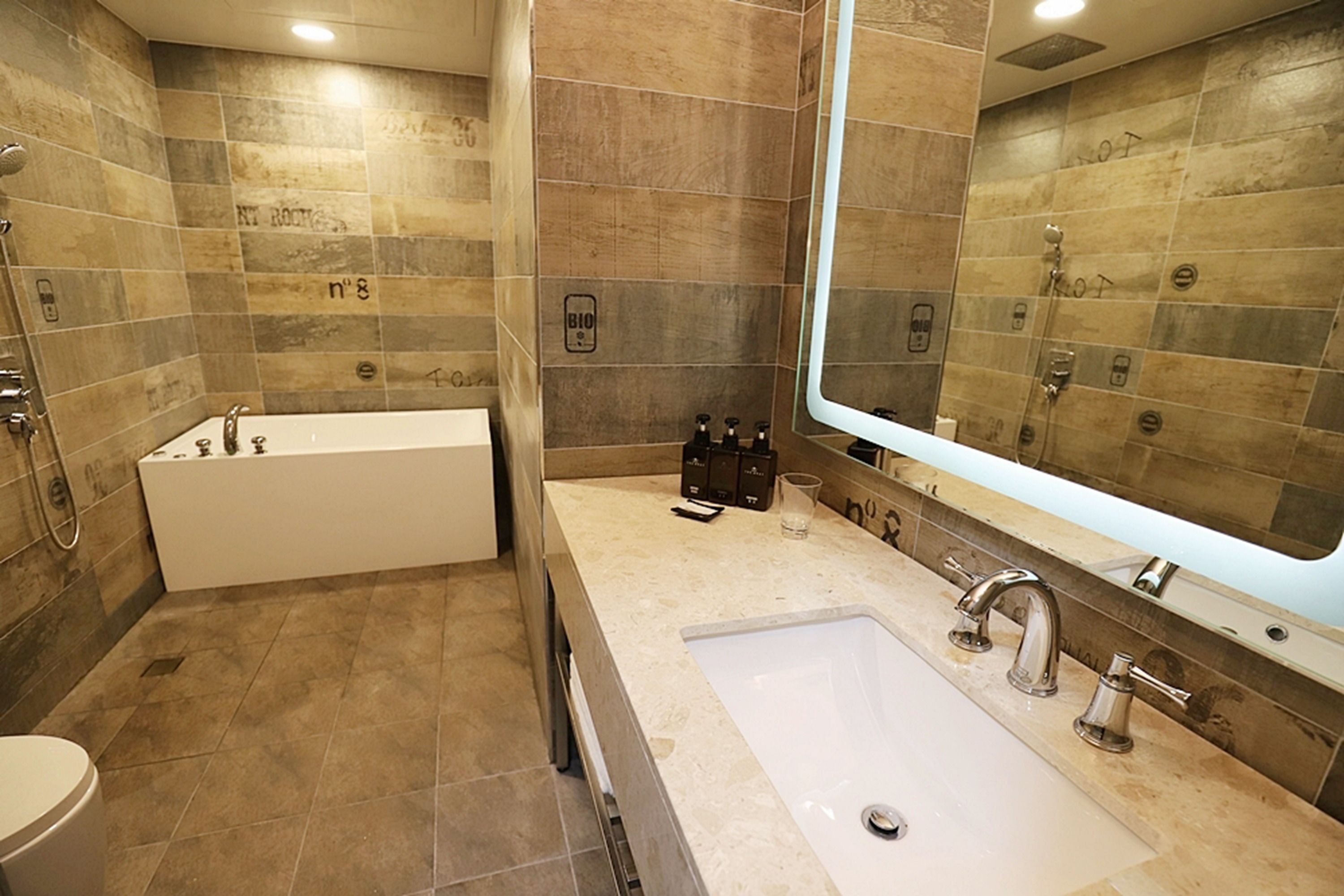 Un baño moderno con bañera, lavabo y un espejo grande.