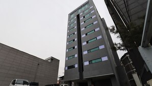 Un hotel de varios pisos con diseño moderno, que destaca por su entrada principal y numerosas ventanas.