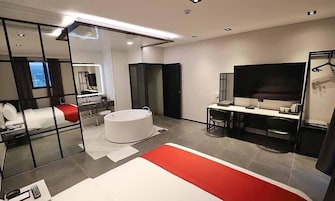 Una habitación de hotel moderna con una cama grande, un baño independiente, un escritorio con silla y un televisor de pantalla plana.