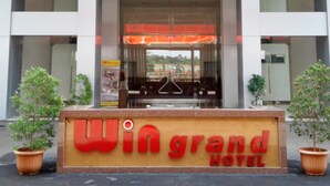 The entrance to Win Grand Hotel with a prominent sign, glass doors, and potted plants. - Win Grand Hotel (Bekasi)