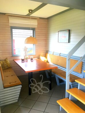 Um quarto aconchegante com um banco de madeira, uma mesa com um copo e um lustre.