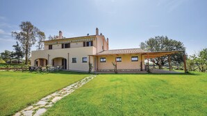 Une maison à deux étages dotée d’un patio couvert et d’une pelouse bien entretenue.