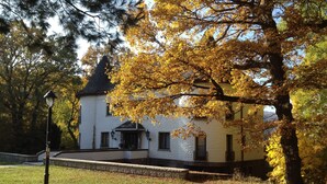 A white building with a black roof, surrounded by trees with yellow leaves.