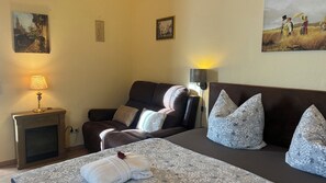 A room with a bed, a sofa, a fireplace, and wall-mounted lamps.