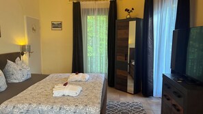 Une chambre d’hôtel avec un lit, une télévision, une armoire et une fenêtre avec des rideaux.