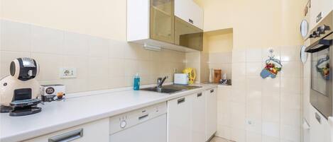 Een moderne keuken met witte kastjes, een Bosch vaatwasser, een koffieapparaat en een spoelbak.